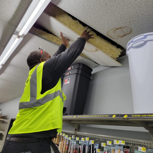 Man removing a stores ceiling tile