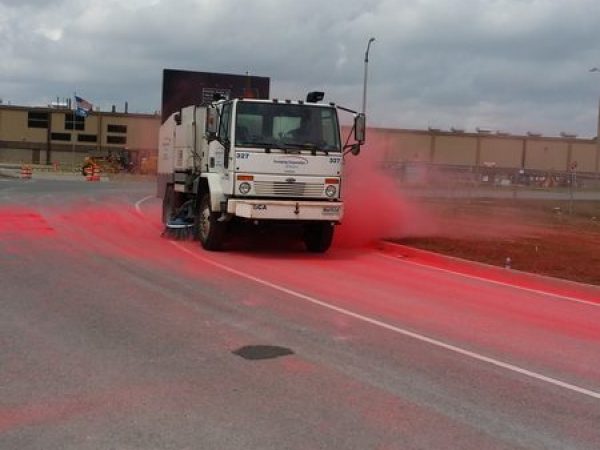 Truck cleaning red powder off the road