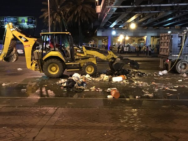 A yellow construction vehicle cleaning up street trash